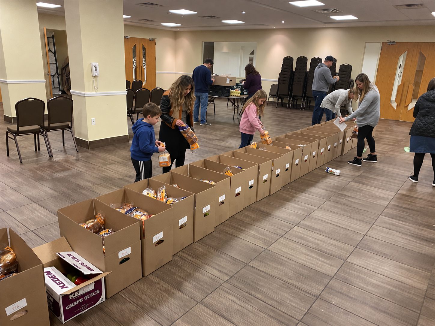 Volunteers, including families with children, packing Shabbos boxes